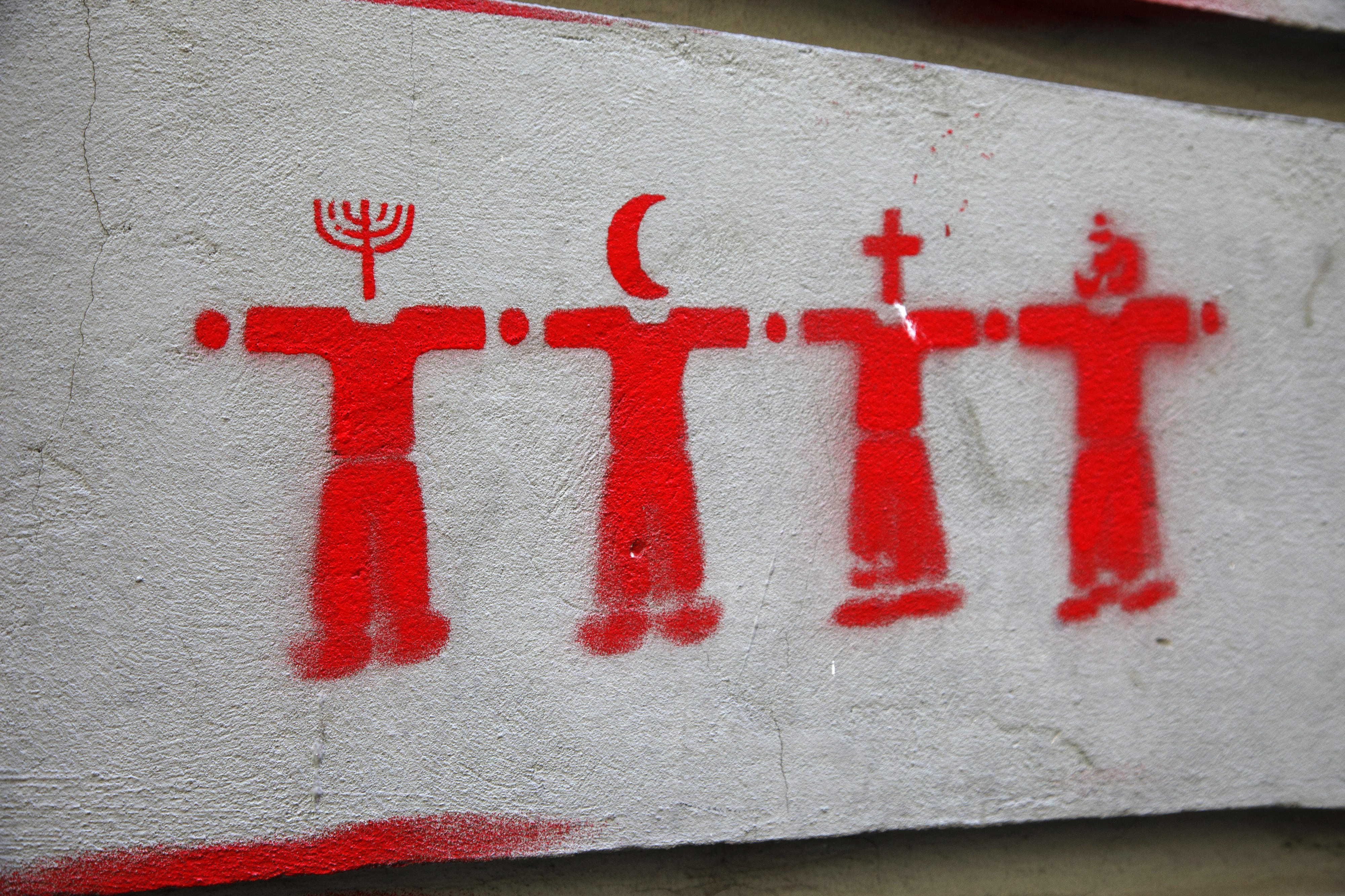 Symbolic image of world religions, depicted in the form of graffiti on a cement surface: four red figures symbolise different religions